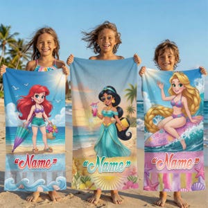Op de afbeelding: Drie strandlakens met stripfiguren. E&eacute;n laken heeft Ariel, een ander Jasmine en de derde Rapunzel. Elk laken heeft een strandachtergrond en het woord "Name" in een scriptlettertype. De lakens worden door kinderen op een zandstrand vastgehouden.