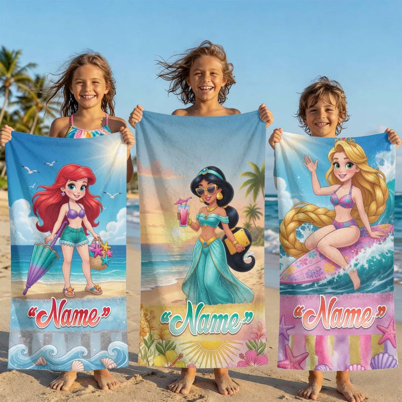 Op de afbeelding: Drie strandlakens met stripfiguren. E&eacute;n laken heeft Ariel, een ander Jasmine en de derde Rapunzel. Elk laken heeft een strandachtergrond en het woord "Name" in een scriptlettertype. De lakens worden door kinderen op een zandstrand vastgehouden.