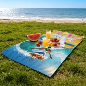 May include: A beach blanket featuring a cartoon snowman surfing a wave, with the text "Summer". The blanket is blue with a colorful design. A watermelon slice, strawberries, and orange juice are on the blanket.