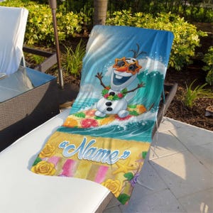 May include: A beach towel featuring a cartoon snowman wearing sunglasses and a floral lei, surfing a wave. The towel has a blue and yellow beach scene with the word "Name" and floral accents.