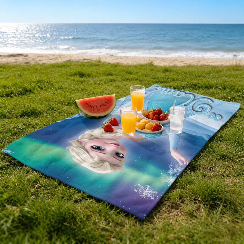 May include: A blue beach blanket featuring a cartoon character with blonde hair and blue eyes, with a background of an aurora borealis. The blanket is spread on green grass with a watermelon slice, fruit, and drinks.