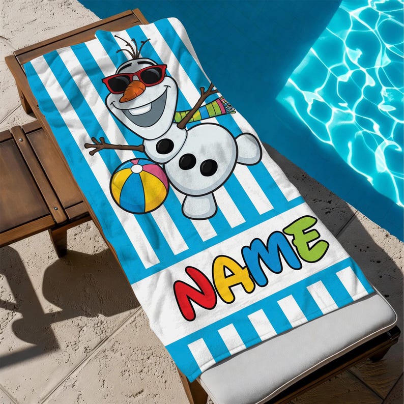 K&ouml;nnte beinhalten: Ein Strandtuch mit blau-wei&szlig;en Streifen, das einen Cartoon-Schneemann mit Sonnenbrille und einem Strandball zeigt. Das Wort "NAME" ist in bunten Buchstaben am unteren Rand aufgedruckt. Das Handtuch liegt auf einer Holzliege.