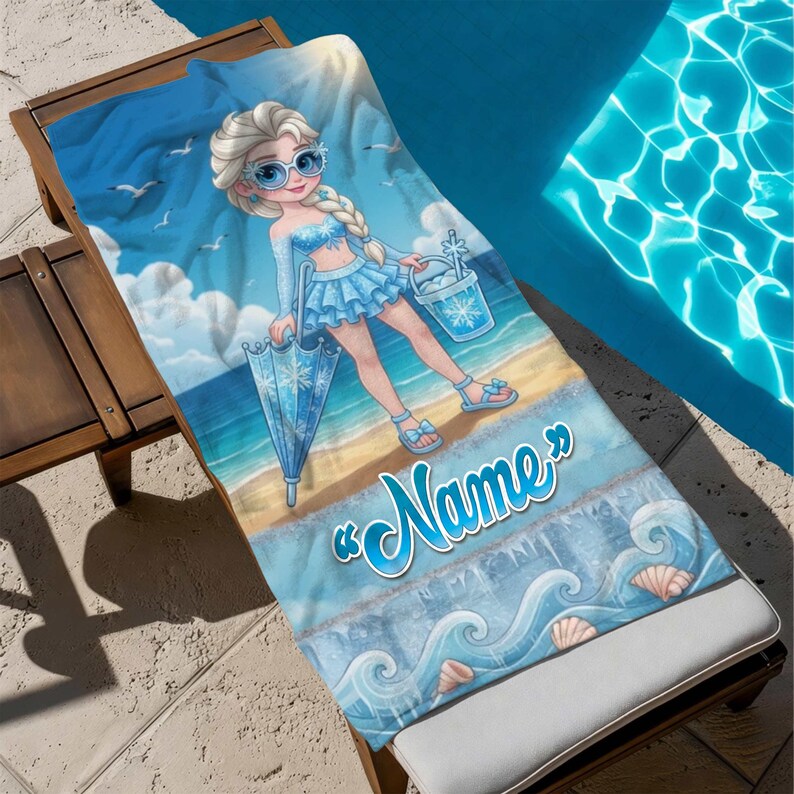 Op de afbeelding: Een blauwe strandlaken met een stripfiguur in een blauwe outfit, zonnebril en paraplu. De handdoek heeft een strandsc&egrave;ne met golven, schelpen en het woord "Name" in een scriptlettertype. De handdoek ligt op een houten ligstoel.