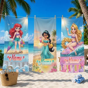 Op de afbeelding: Drie strandlakens met illustraties van cartoonprinsessen. E&eacute;n toont een roodharige prinses met een paraplu, een ander een prinses met een drankje en de derde een surfende prinses. Elke handdoek heeft onderaan een naamplaatshouder.