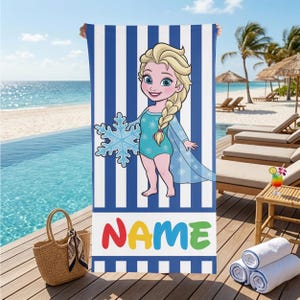 K&ouml;nnte beinhalten: Ein blau-wei&szlig; gestreiftes Strandtuch mit einer Cartoon-Illustration einer Figur, die eine Schneeflocke h&auml;lt. Das Wort "NAME" steht in bunten Buchstaben am unteren Rand. Die Figur tr&auml;gt einen blauen Badeanzug und einen Umhang.