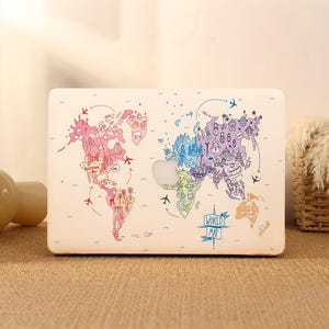 May include: A white laptop case featuring a colorful world map design. The map is illustrated with various landmarks, airplanes, and the text "WORLD MAP". The case has a smooth finish and a cut-out for the Apple logo.