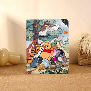May include: A rectangular notebook featuring a colorful illustration of Winnie the Pooh and his friends. The image includes Pooh, Tigger, Piglet, Eeyore, Rabbit, Owl, Kanga, Roo, and Gopher in a forest setting with autumn leaves.