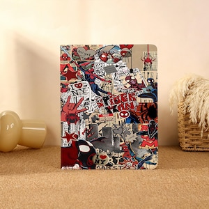 May include: A notebook featuring a collage of Spider-Man comic book art. The design includes various Spider-Man illustrations, the text "I NY", and other comic book elements in red, black, and white. The notebook has a beige background.