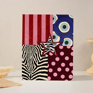 Può includere: Un'opera d'arte quadrata decorativa con un design patchwork. Presenta una stampa zebrata, strisce rosa, pois e motivi a occhio blu. Una stella zebrata con un contorno rosso è centrata sull'opera d'arte.