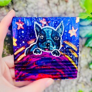 May include: A white ceramic mug with a black handle and the text "But First, Coffee" in a bold, black font. The mug is filled with a dark liquid, likely coffee, and sits on a light-colored surface.