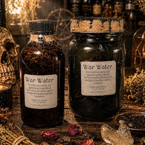 Può includere: Due barattoli di vetro etichettati War Water, uno con tappo nero e ciondolo a forma di teschio, l'altro con coperchio avvolto da spago. Entrambi contengono liquido scuro e materiale botanico, con etichette bianche di protezione spirituale.