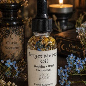 Könnte beinhalten: Eine klare Glasflasche mit schwarzem Tropferverschluss, beschriftet mit "Forget Me Not Oil", gefüllt mit getrockneten Blumen. Das Etikett trägt auch die Aufschrift "Imprint Bond Connection". Blaue Vergissmeinnicht und eine brennende Kerze sind im Hintergrund.