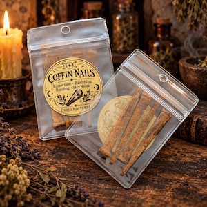 May include: Two clear plastic resealable bags containing rusty metal coffin nails. The front bag features a circular tan label with the text COFFIN NAILS, Protection, Banishing, Binding, Hex Work, and Curio Nocturne, along with a coffin illustration.