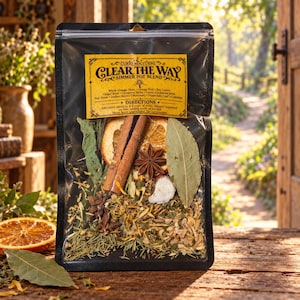 May include: A clear plastic pouch containing a Curio Nocturne Clear The Way simmer pot blend. The label lists ingredients including orange slices, cinnamon sticks, and star anise. Visible contents include dried orange, cinnamon, and herbs.