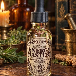 Puede incluir: Un frasco cuentagotas de vidrio transparente lleno de líquido dorado y hierbas botánicas. La etiqueta presenta texto negro que dice RITUAL OIL ENERGY MASTERY POWER CONTROL ASCENSION CURIO NOCTURNE con ilustraciones de luna y cristal.