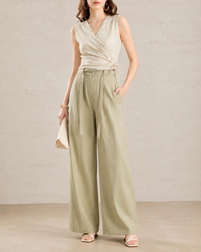 Puede incluir: Un top sin mangas cruzado con un sutil estampado floral, combinado con pantalones de cintura alta y pernera ancha en un suave tono verde. El conjunto incluye un cintur&oacute;n a juego y un clutch de color neutro, creando un conjunto coordinado y elegante.