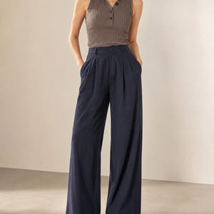Puede incluir: Un top sin mangas de punto acanalado marr&oacute;n apagado con cuello y tres botones. Combinado con pantalones de pierna ancha azul marino. Los pantalones tienen cintura alta y pliegues en la parte delantera.
