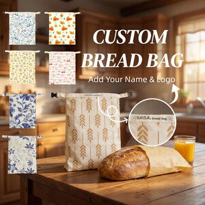 May include: A custom bread bag with a wheat stalk pattern, featuring a roll-top closure with a black buckle. The bag displays the text VAIDA's bread bag. Several other bread bags with various floral and fruit patterns are shown in the background.