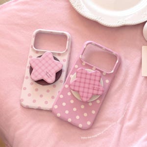 May include: Two phone cases with white polka dots on pink backgrounds, each featuring a star-shaped magnetic stand. The star stands have a pink and white checkered pattern and the text Light chance Nicecy printed on the front surface.