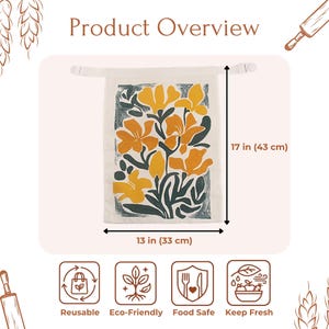 May include: A rectangular off-white fabric bag featuring a yellow and dark green floral print. The bag measures 13 inches wide by 17 inches high. It includes a top closure strap and is labeled with icons for reusable, eco-friendly, food safe, and keep fresh.