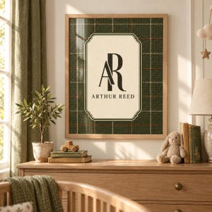 May include: A framed wall art print featuring a dark green and brown plaid background with a central cream-coloured rectangular label. The label displays the black monogram letters AR above the name Arthur Reed in a classic serif font.
