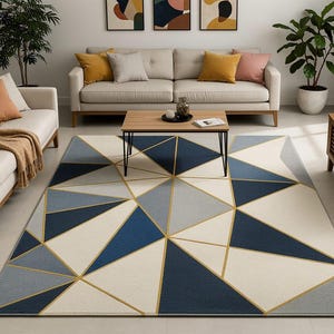 May include: A rectangular area rug featuring a geometric pattern of triangles in shades of navy blue, light gray, and cream. The design is accented by thin, intersecting gold lines that create a structured, multi-faceted visual composition.
