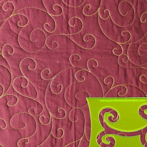 May include: Close-up of a quilted fabric with a burgundy background and gold thread swirls. A green acrylic quilting template is in the lower right corner. The template has a curved design and the website address www.parrsfreemotionrulers.com.