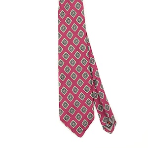 May include: A necktie featuring a vibrant magenta background with a repeating pattern of small, diamond-shaped motifs. Each diamond contains a dark green centre surrounded by a white border. The tie has a pointed end and a visible brand label on the back.