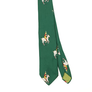 Puede incluir: Una corbata de color verde oscuro con un patrón repetitivo de jugadores de polo sobre caballos blancos. Cada jugador viste una camisa roja y un casco amarillo, sosteniendo un mazo. La corbata tiene una punta y un forro verde claro visible.