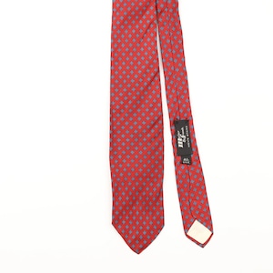 Op de afbeelding: Een rode zijden stropdas met een herhalend blauw ruitpatroon. De stropdas heeft een label met de tekst "mr & frank" en "all silk". De stropdas wordt tegen een witte achtergrond getoond.
