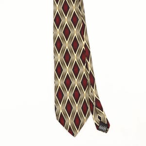 Peut inclure: Une cravate présentant un motif géométrique répétitif en losanges dans des tons de rouge profond, gris foncé et beige clair. Le design se compose de formes en losange interconnectées par de fines lignes. Une étiquette noire est fixée au dos.