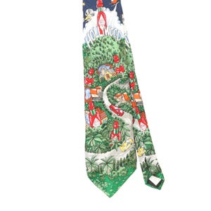 May include: A necktie featuring a colourful graphic print of the Hollywood sign, palm trees, houses, and red hot sauce bottles. The design includes a winding road, a red car, a yellow car, and a dark blue sky at the top with the text Hollywood.