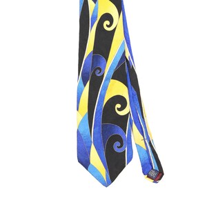 May include: A necktie featuring a bold, abstract pattern of swirling shapes in vibrant yellow, bright blue, and deep black. The fabric displays a smooth, satin-like finish with a pointed tip and a small label on the back indicating it is made in the USA.