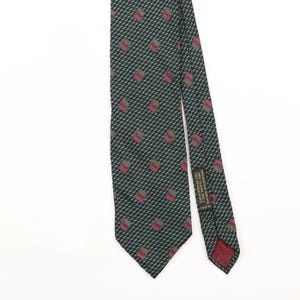 Può includere: Una cravatta verde scuro con un motivo ripetuto di piccoli quadrati marroni e rosa. Sul retro è presente un'etichetta in tessuto nero con la scritta 100% PURE SILK, DRY CLEAN ONLY, NETTOYAGE A SEC e il codice CA 57510.