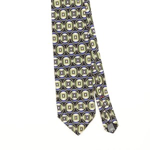 Peut inclure: Une cravate présentant un motif géométrique répétitif de cercles noirs entourant des formes vert sauge et bleues avec des carrés centraux. Le motif est sur fond noir et la cravate comporte une petite étiquette au dos près de la pointe.