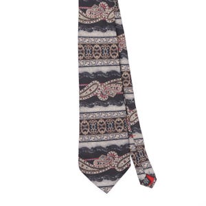 May include: A necktie featuring a dark background with horizontal bands of paisley patterns, intricate scrollwork, and wavy lines in shades of gray, black, and muted red. A small black label on the back reads 100% Italian Silk.