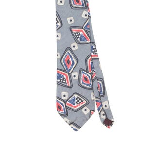 May include: A grey necktie featuring a repeating pattern of diamond shapes outlined in black. Each diamond contains a red center, a blue section, and a small black and white checkered square. Small cream-colored squares with black dots are scattered between the diamonds.