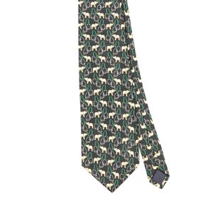 May include: A dark grey necktie featuring a repeating pattern of small cream-coloured elephants paired with green and white stirrups. The tie has a pointed end and a dark blue fabric label visible on the back side of the narrow tail section.