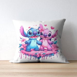May include: A square white throw pillow featuring a colorful illustration of two cartoon creatures, one blue and one pink, standing on a pink dripping surface surrounded by pink flowers and small floating hearts against a plain white background.