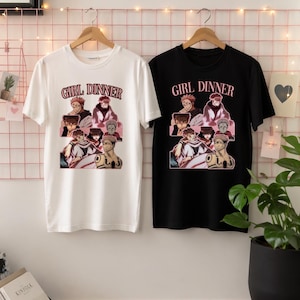 Könnte beinhalten: Ein weißes T-Shirt und ein schwarzes T-Shirt, jeweils mit dem Text GIRL DINNER und einer grafischen Collage eines Anime-Charakters mit stacheligen Haaren und Gesichtsmarkierungen. Beide T-Shirts haben kurze Ärmel und einen Rundhalsausschnitt.