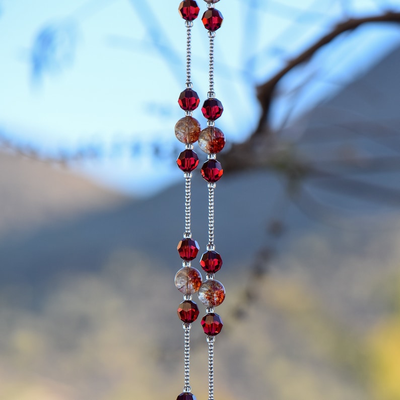 Puede incluir: Un collar de cadena de plata con cuentas de vidrio rojas y transparentes. Las cuentas son facetadas y tienen un acabado brillante.