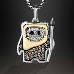 May include: A silver pendant necklace with a cartoon-like figure. The figure has a gold-coloured face and is embellished with gemstones. It holds a spear and has black gemstone eyes. The necklace chain is silver.