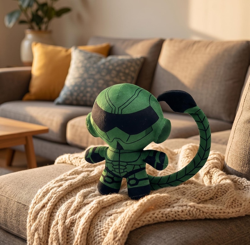 Op de afbeelding: Een groene pluche schorpioen met zwarte accenten, waaronder een gesegmenteerde staart en een gezichtsmasker. De schorpioen staat op een cr&egrave;mekleurige gebreide deken, met een bank en kussens op de achtergrond.