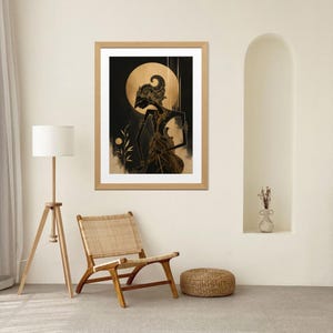 Op de afbeelding: Een ingelijste kunstdruk met een gestileerde figuur met een uitgebreide hoofdtooi en gedetailleerde kleding, tegen een donkere achtergrond met een gouden maan. Het kunstwerk zit in een houten lijst.