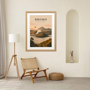 May include: Framed art print featuring a landscape illustration of Mount Bromo in East Java, Indonesia. The artwork depicts a volcanic mountain range with a rising sun and the word "Bromo" at the top.