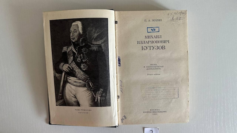 K&ouml;nnte beinhalten: Ein aufgeschlagenes Buch mit einem schwarz-wei&szlig;en Portr&auml;t von Mikhail Kutuzov auf der linken Seite und einer Titelseite rechts. Der Text lautet P. A. Zhilin, Mikhail Illarionovich Kutuzov, Zhizn i Polkovodcheskaya Deyatelnost, Moskva Voennoe Izdatelstvo 1983.