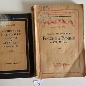 K&ouml;nnte beinhalten: Zwei alte B&uuml;cher mit gealterten Papierumschl&auml;gen. Das linke Buch hat einen schwarzen Rand und kyrillischen Text, darunter 'ЭКСПЕДИЦИЯ РУССКОГО ФЛОТА В АРХИПЕЛАГ'. Das rechte Buch ist hellbraun mit roten R&auml;ndern und kyrillischem Text, darunter 'РОССИЯ И ТУРЦИЯ В XVI-XVII ВВ'.