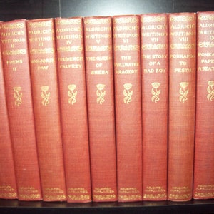 May include: A set of ten red hardcover books titled Aldrich's Writings, featuring gold embossed lettering and floral motifs on the spines. The collection includes volumes of poems, stories, and papers by Thomas Bailey Aldrich, published by Houghton Mifflin.