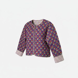 May include: A quilted jacket in a deep purple hue featuring a repeating floral pattern with red blossoms and green leaves. The garment has long sleeves with light-colored striped cuffs, a round neckline, and an open front design with no buttons.