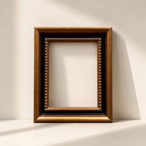Puede incluir: Un marco de fotos rectangular con un marco exterior dorado y un marco interior negro. El marco tiene un borde decorativo con cuentas. El marco está vacío, listo para una foto o una obra de arte.